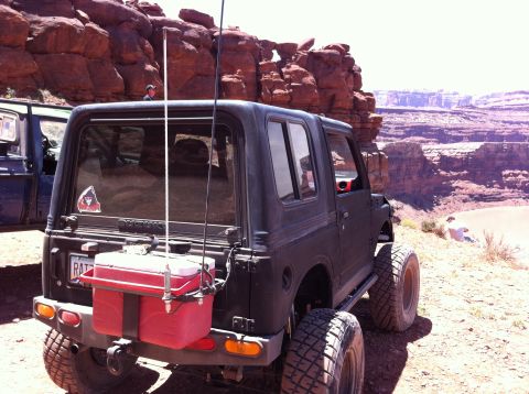 1987 Suzuki Samurai - A 1987 Suzuki Samurai is parked on a rocky trail, with another vehicle visible to the left and a canyon in the background.