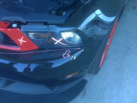 1973 Ford Mustang - A black car's front end is visible, red accents and orange markings on the headlight and grille.