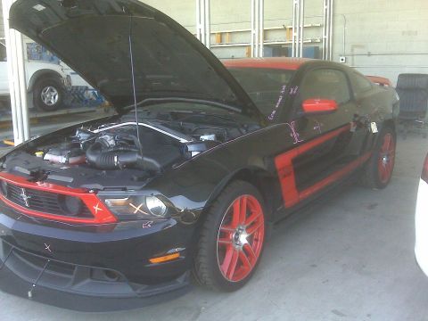 1973 Ford Mustang - Black Ford Mustang with red accents and hood open, parked indoors.
