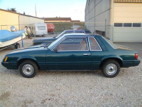 1991 Ford LTD Crown Victoria - A green coupe with a tan interior is parked outdoors next to another vehicle and a trailer.