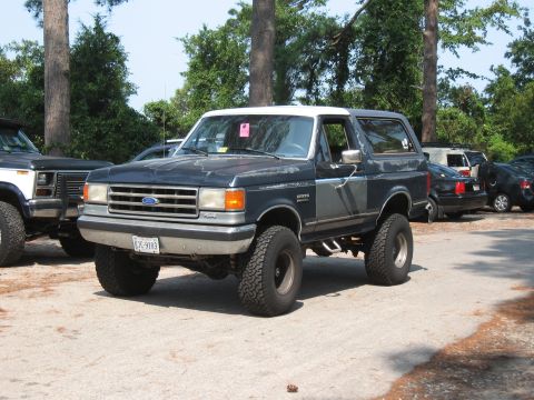 1994 Ford Bronco - This lifted 1994 Ford Bronco is parked outdoors with other vehicles visible in the background.
