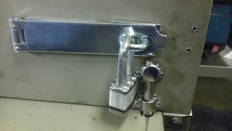 1989 Ford Bronco - A heavy-duty padlock secures a metal latch on a cabinet or door.