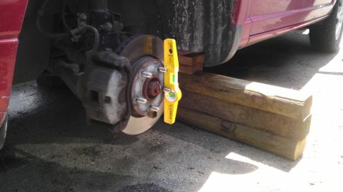 2007 Dodge Caliber - A yellow bubble level is attached to the brake rotor of a car that is supported by wooden blocks.