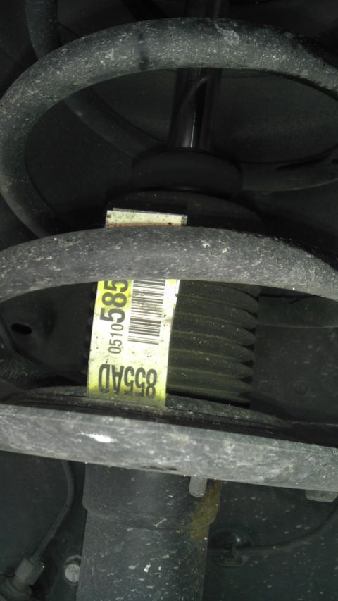 2007 Dodge Caliber - A close-up view of a car's suspension system, a yellow identification sticker with barcode and alphanumeric codes.