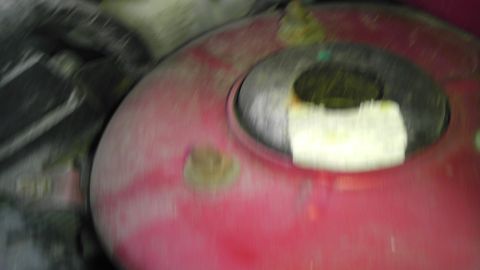 2007 Dodge Caliber - A close-up view of a red engine component with a circular opening covered by white tape.