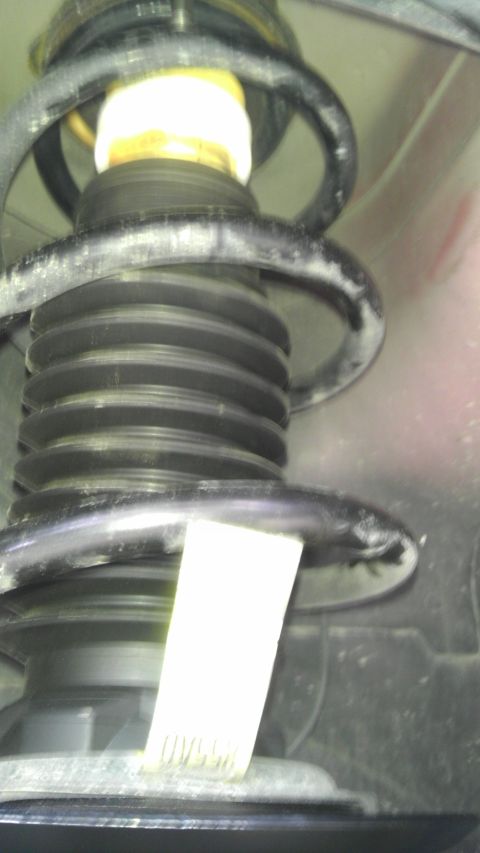 2007 Dodge Caliber - A close-up view of a vehicle's suspension system, a strut and coil spring with a white identification tag.