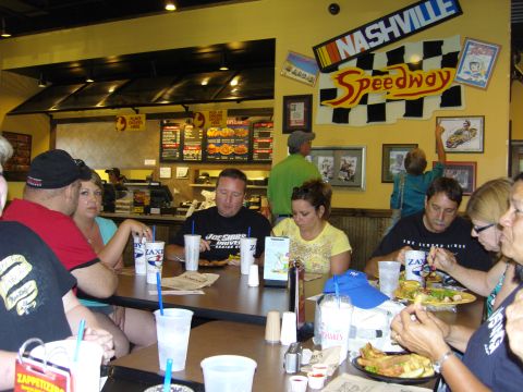 2007 Ford Mustang - A group of people dine at a restaurant racing memorabilia on the walls.