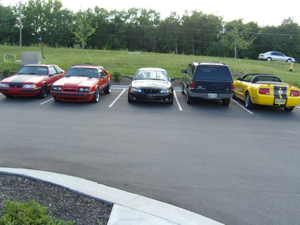 Yellow convertible Mustang with black stripes, rear view