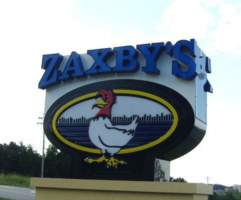 2007 Ford Mustang - A large Zaxby's sign with a cartoon chicken mascot is visible against a bright sky.