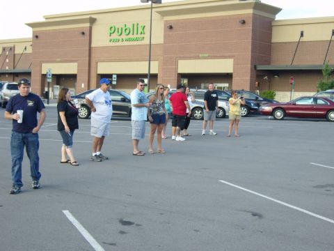 2007 Ford Mustang - A group of people gather in a parking lot outside a grocery store, with several vehicles visible in the background.