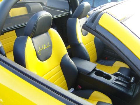 2007 Ford Mustang - The interior of a car features custom yellow and black seats with an embroidered signature on the driver's seat.