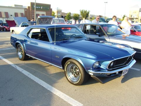 2007 Ford Mustang - A blue 1969 Ford Mustang coupe is parked in a lot, with other vehicles and a Panera Bread in the background.