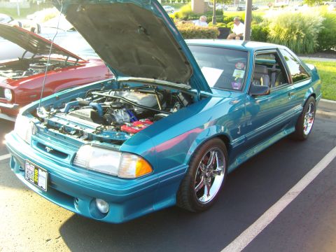 2007 Ford Mustang - A teal Ford Mustang from the late 1980s is displayed with its hood open, parked at an outdoor event.