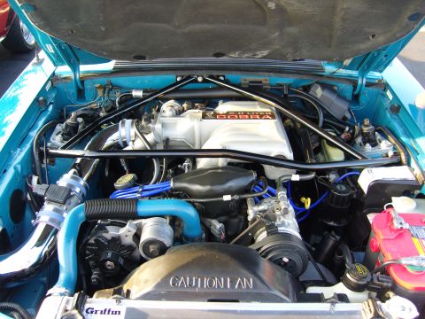 2007 Ford Mustang - The engine bay of a turquoise Ford Mustang shows a "5.0 LITER COBRA" intake manifold and blue hoses.