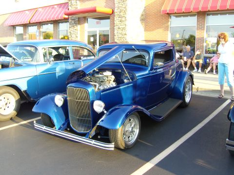 2007 Ford Mustang - A blue 1932 Ford hot rod coupe is parked next to another classic car at a meet.