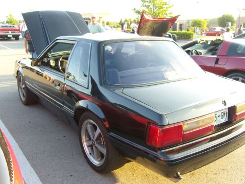 2007 Ford Mustang - A dark green coupe with its hood open is parked at an outdoor event, with other vehicles visible.