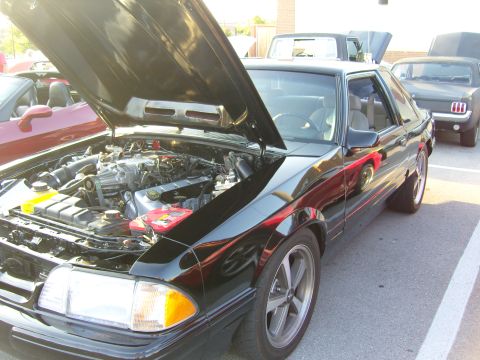 2007 Ford Mustang - A black 1987 Ford Mustang coupe is displayed with its hood open, revealing a supercharged engine, at a car meet.