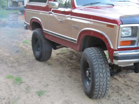 1984 Ford Bronco - Lifted Ford Bronco with two-tone paint and off-road tires.