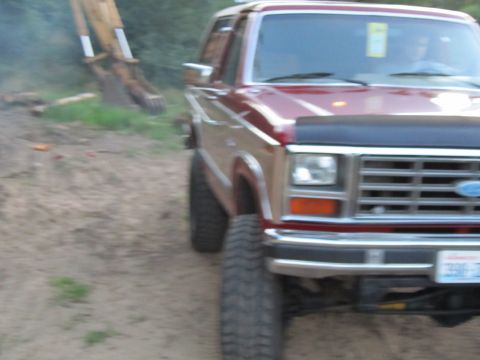 1984 Ford Bronco - This red Ford Bronco features a black bug deflector and large aftermarket tires, suggesting modifications beyond its original factory appea…