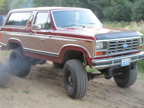 1984 Ford Bronco - Ford Bronco with lifted suspension and large tires, emitting smoke from the rear wheel.