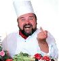 1978 Ford Bronco - A chef in uniform gestures with his middle finger while smiling broadly, with a salad in front of him.