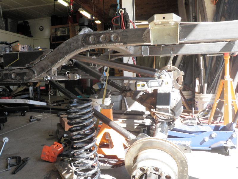 Vehicle frame with suspension parts, including springs and axle, in a workshop