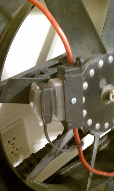 1990 Ford Bronco - This electric fan motor is wired with a red cable and connected through a fuse holder, with a wall outlet nearby.