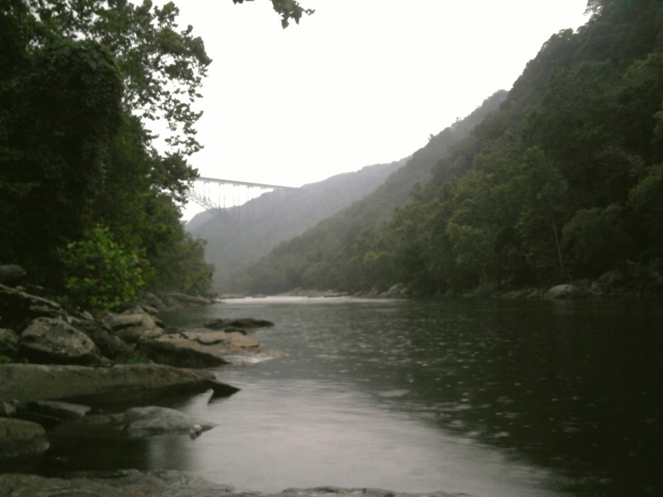 River flowing through a valley with a large bridge in the distance