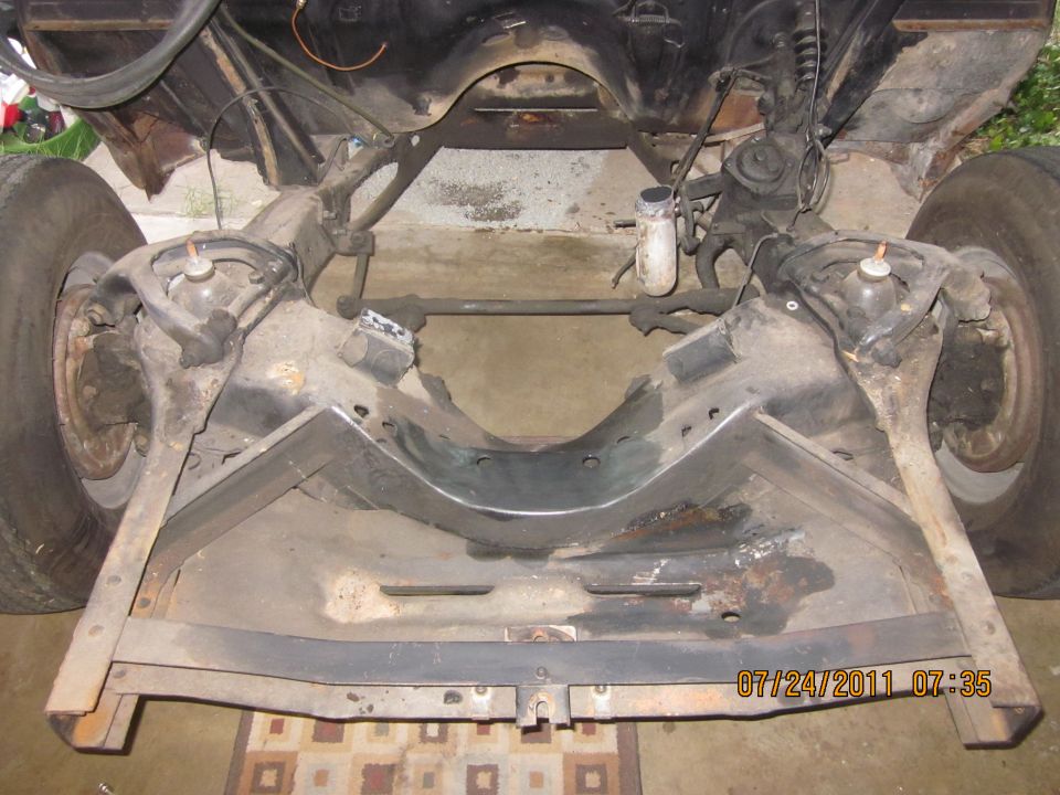 Underside view of a car's frame and front suspension with tires visible