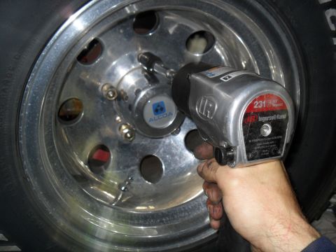 1990 Ford Bronco - Impact wrench removes lug nuts from a chrome wheel with an Alcoa center cap.