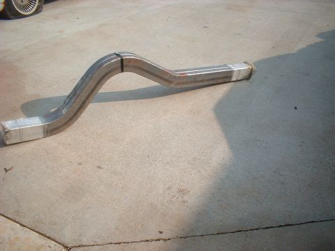 1969 Ford Torino - A bent exhaust pipe section lies on a concrete surface, its ends wrapped and secured with metal bands.
