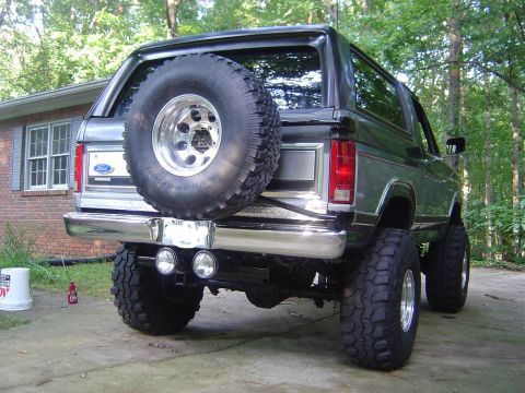 1986 Ford Bronco - This lifted Ford Bronco has a spare tire mounted on the rear door and dual exhaust pipes.