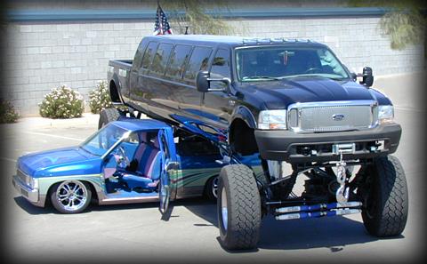 1992 Ford Bronco - A custom-built limousine truck is dramatically displayed, elevated above a lowered pickup truck.