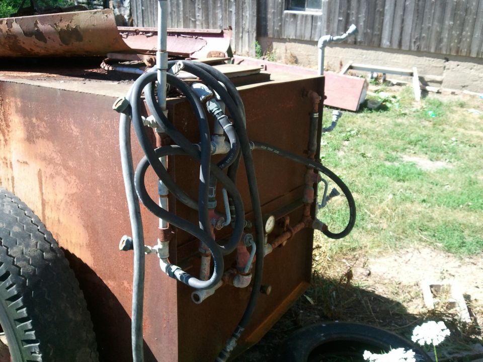 Rusted sprayer tank with coiled hoses and gauges