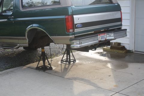 1996 Ford Bronco - Rear view of a green Ford Bronco on jack stands, possibly for repair or modification.