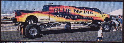 1992 Ford Bronco - This heavily modified truck features custom flame graphics and "BLUE MEDIA VEHICLE GRAPHICS" branding.