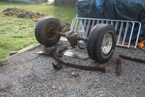 1996 Ford Bronco - A disassembled rear axle assembly with leaf springs and shocks is laid out on a gravel surface.