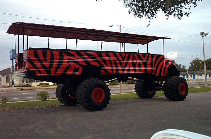 Custom monster truck with tiger stripes and a canopy, parked on asphalt