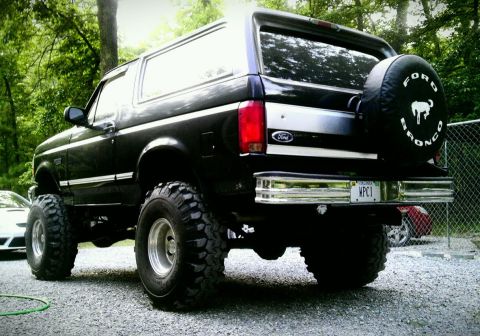 1993 Ford Bronco - Rear view of a lifted 1993 Ford Bronco with large off-road tires and a spare tire cover.