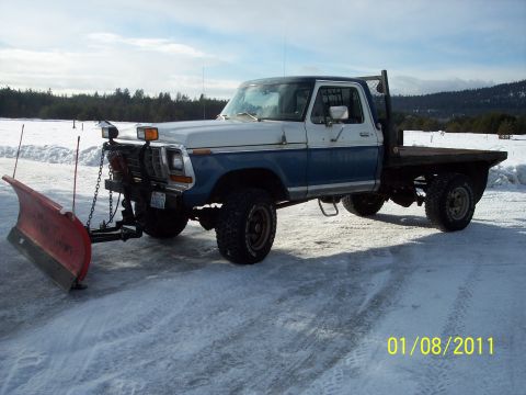1973 Ford F-250 - This 1973 Ford F-250 pickup truck is equipped with a snow plow and flatbed, ready for winter conditions.