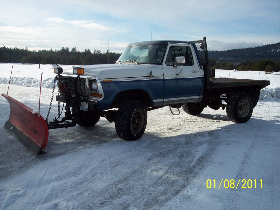 1973 Ford F-250 pickup truck, two-tone blue and white, with a front-mounted snow plow and flatbed