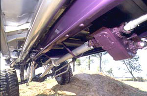 1992 Ford Bronco - Undercarriage of a vehicle with a purple frame and drive shaft is visible from a low angle.