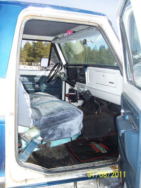 1973 Ford F-250 - The interior of a pickup truck shows a worn bench seat and dashboard with a floor mat visible.