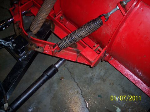 1973 Ford F-250 - The photo shows a close-up view of the mechanical components of a snow plow, including springs and a hydraulic cylinder.
