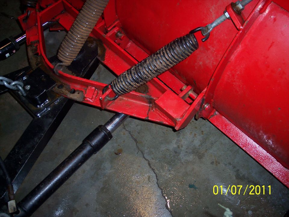 Close-up of a red snow plow's spring and hydraulic cylinder
