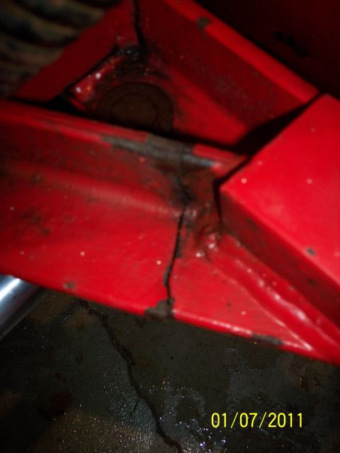 1973 Ford F-250 - Close-up of a damaged red metal component, showing rust and a significant crack.