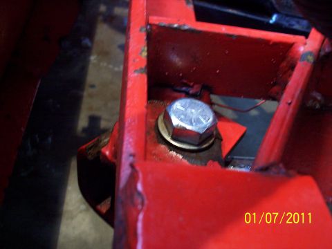 1973 Ford F-250 - A close-up view shows a large bolt securing red painted metal components, with a date stamp visible in the corner.