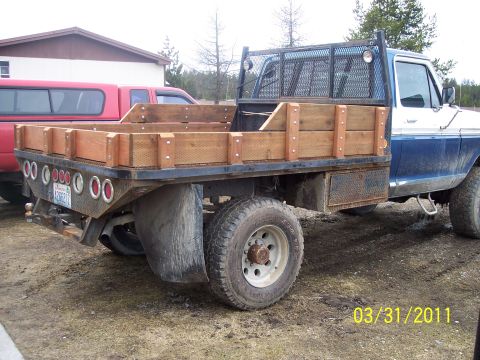 1973 Ford F-250 - Three-quarter rear view of a blue and white two-tone Ford pickup converted to a steel flatbed with wooden stake sides, expanded-metal heada…