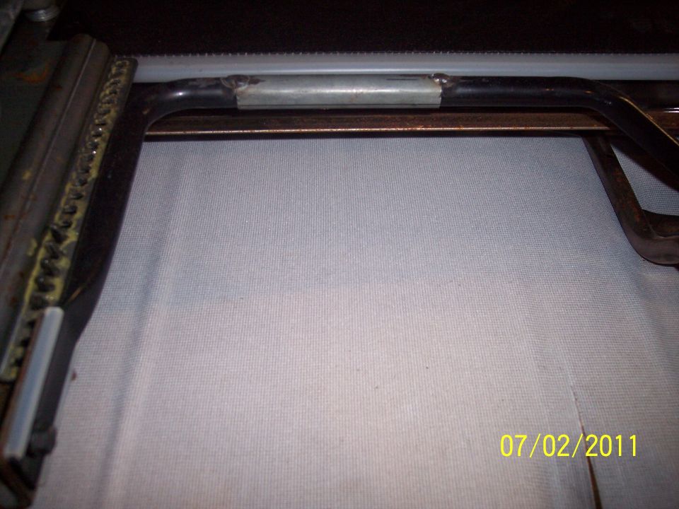 Welded splice sleeve on a bent steel seat frame tube beside a rusty slider track