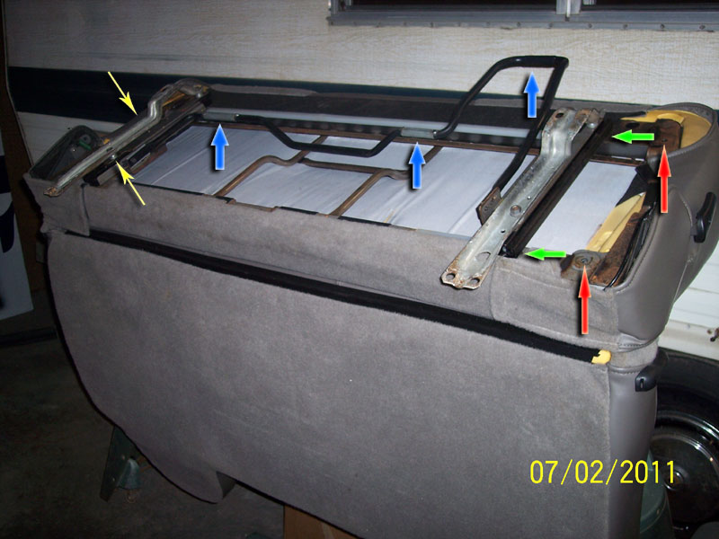 Underside of gray bench seat with slider rails, arrows marking mounting bolts and brackets